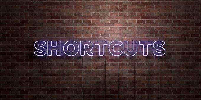A neon sign that says SHORTCUTS against a brick wall