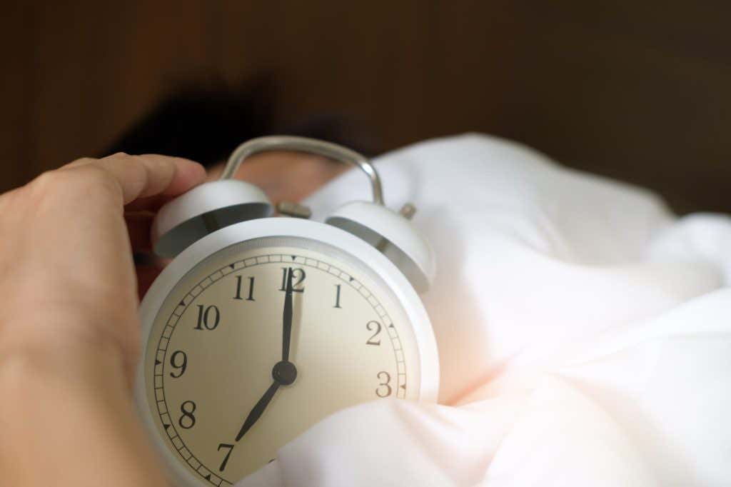 Person holding an alarm clock in bed