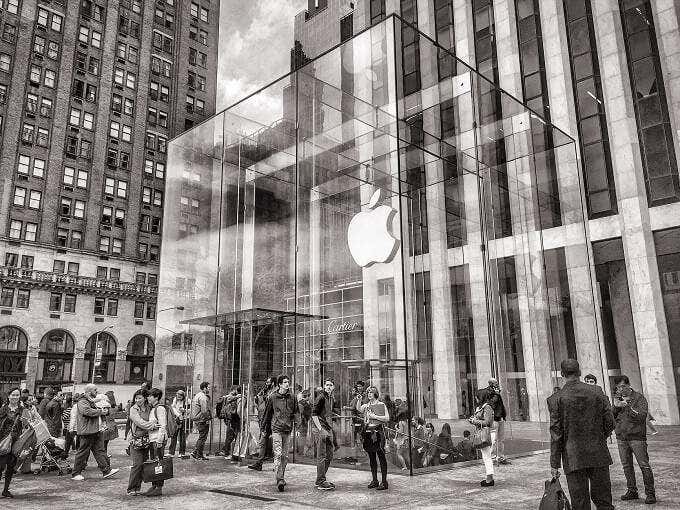 People standing outside of a glass Apple Store