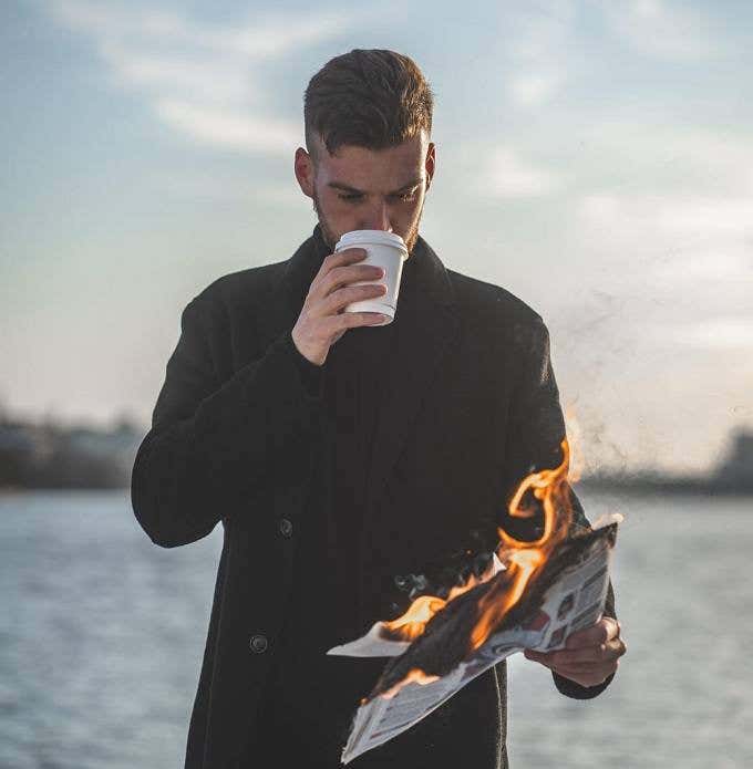 Man reading a newspaper that is on fire