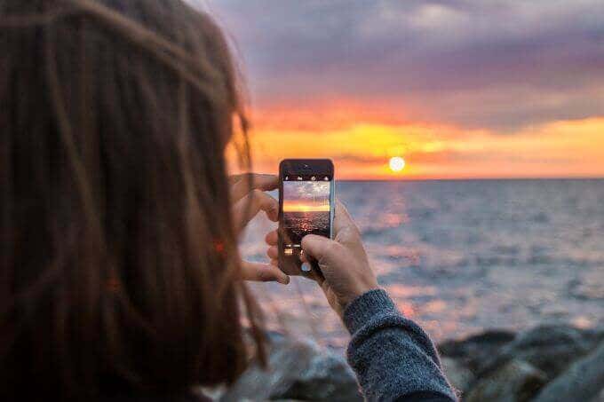 Someone taking a photo of a sunset on an iPhone 