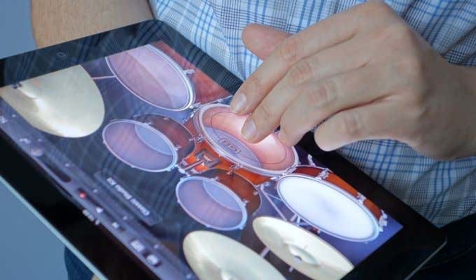 Someone tapping on a virtual drum kit on an iPad 