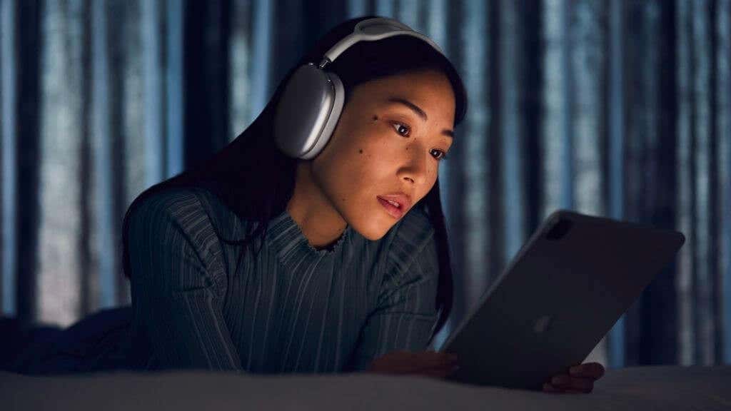 A woman wearing AirPad Max headphones looking at an iPad