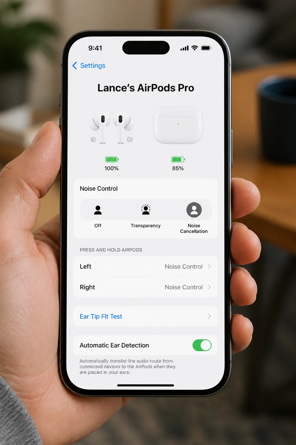 iOS Settings with a connected AirPods name shown near the top of the screen and the AirPods charging case open nearby