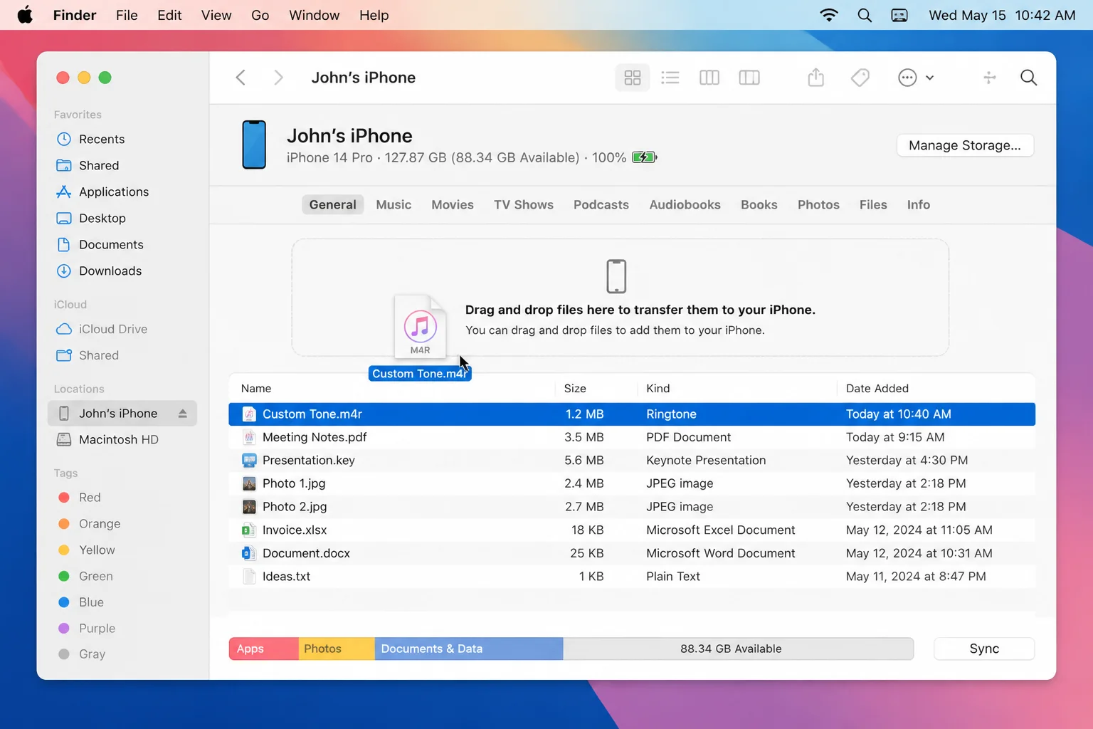 Finder window with a connected iPhone selected under Locations and a Custom Tone.m4r file being dragged onto the iPhone device page